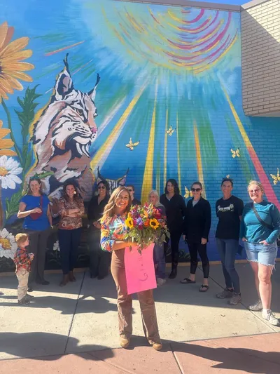 DIA mural — bobcats, sun, and florals on exterior brick