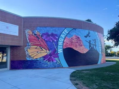 Wingate Elementary — exterior curved brick mural with monarch, WINGATE lettering, and Explorers circular panel