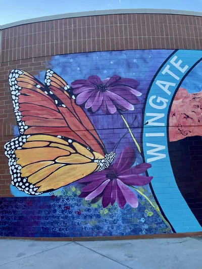 Wingate Elementary mural — monarch butterfly, purple flowers, starry sky, and ROYGBIV handprints along the wall
